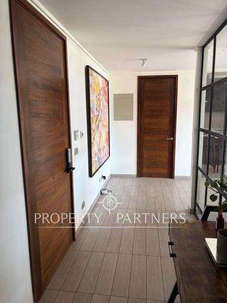 Pasillo con piso cerámico claro y puertas de madera, decorado con cuadro colorido. Pasillo con piso cerámico claro y puertas de madera, decorado con cuadro colorido.